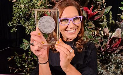 Professor Anita Heiss holding a trophy and smiling