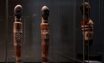 Three carved statues in a glass case 