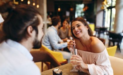 A man and a woman on a date, the woman holding a drink