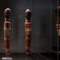 Three carved statues in a glass case 