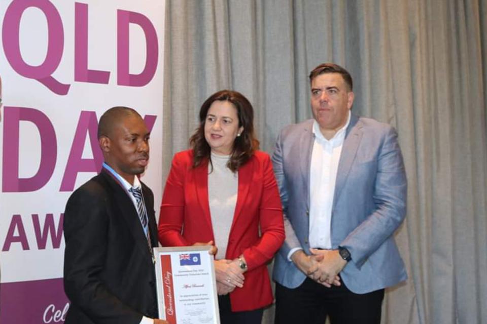 A man holds a certificate alongside a woman and man.