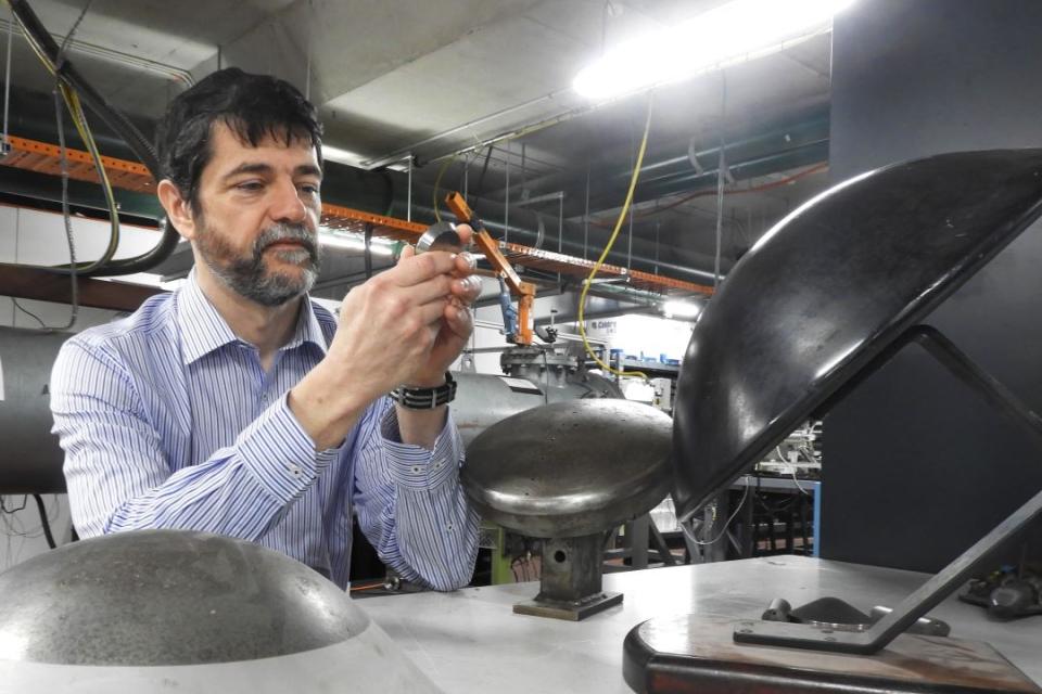 Dr David Gildfind in the UQ hypersonics lab with models of re-entry capsules.