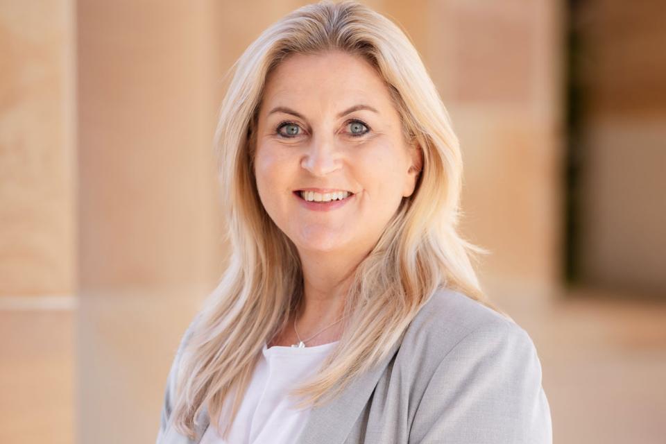 Associate Professor Gabby Walters in a grey blazer standing in the Great Court.