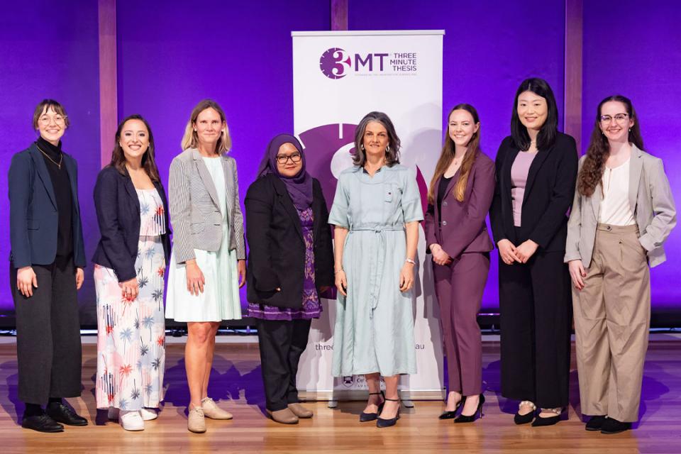 A lineup of women across a stage with a purple background.