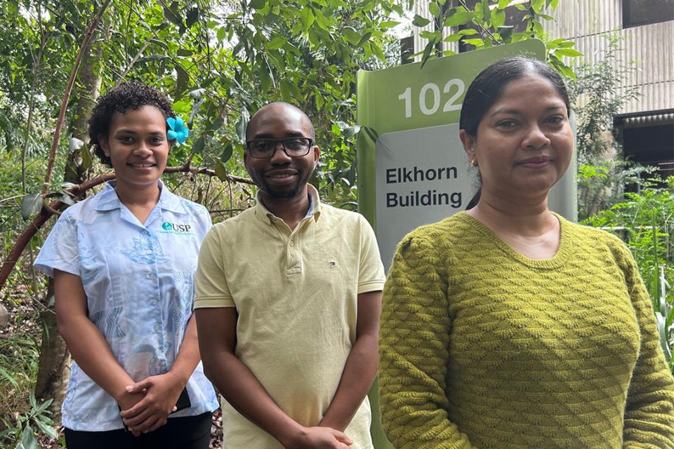 three people stand outside a building at UQ 