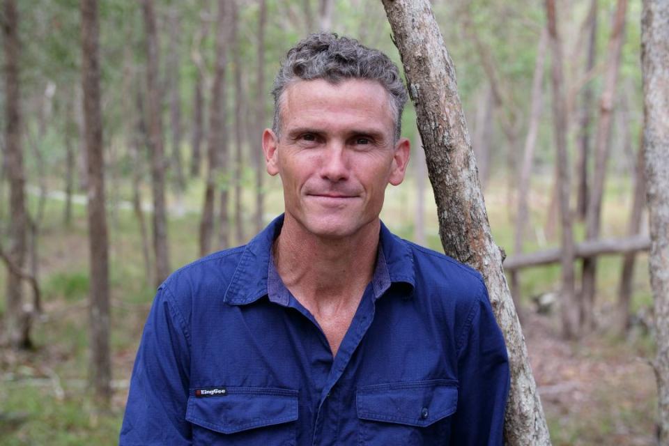A man leaning against a tree