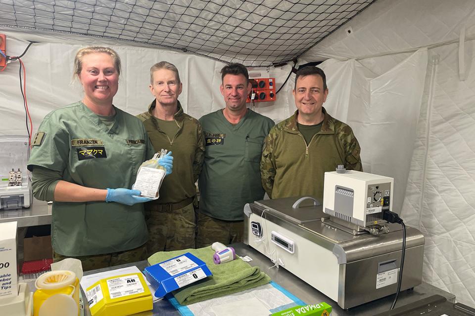 Military staff standing behind a table where blood platelets are being processed