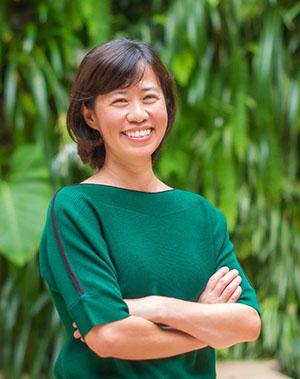 A woman in a green top smiles at the camera.