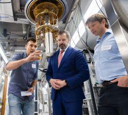 Three men look at equipment in a laboratory.