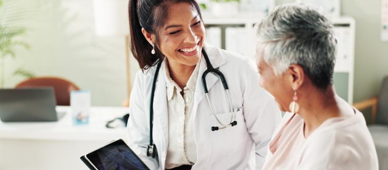 A doctor and a patient smile at each other.