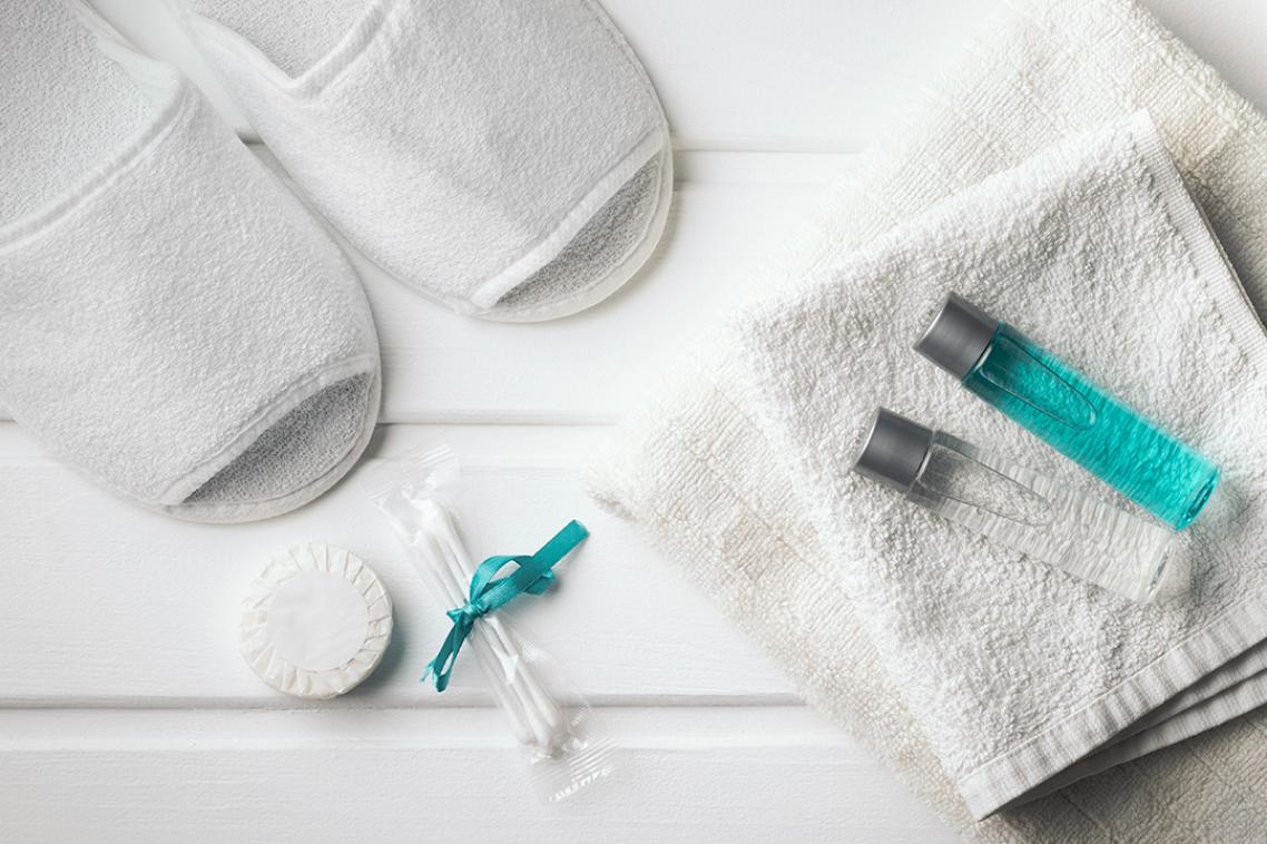 A photo of hotel slippers, soaps and towel.