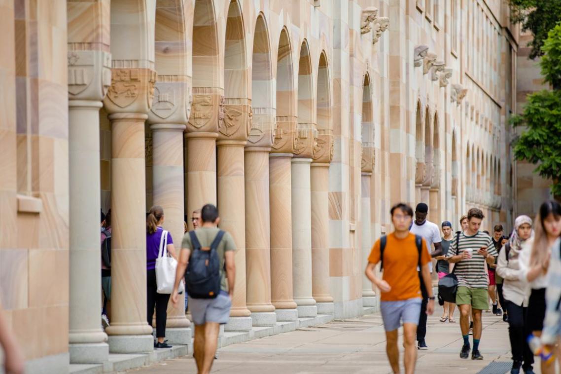 Students walking beside the sandstone builings that surround UQ's Great Court