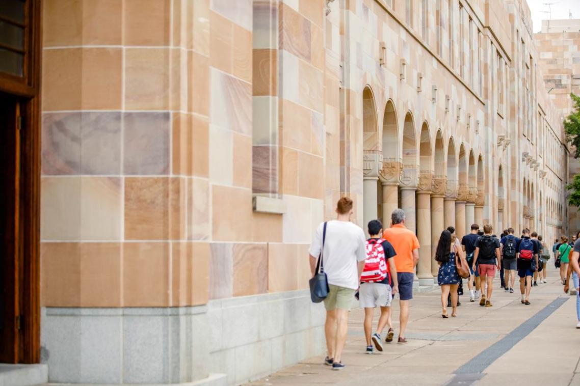 Students walking along sandstone builings that surround UQ's Great Court