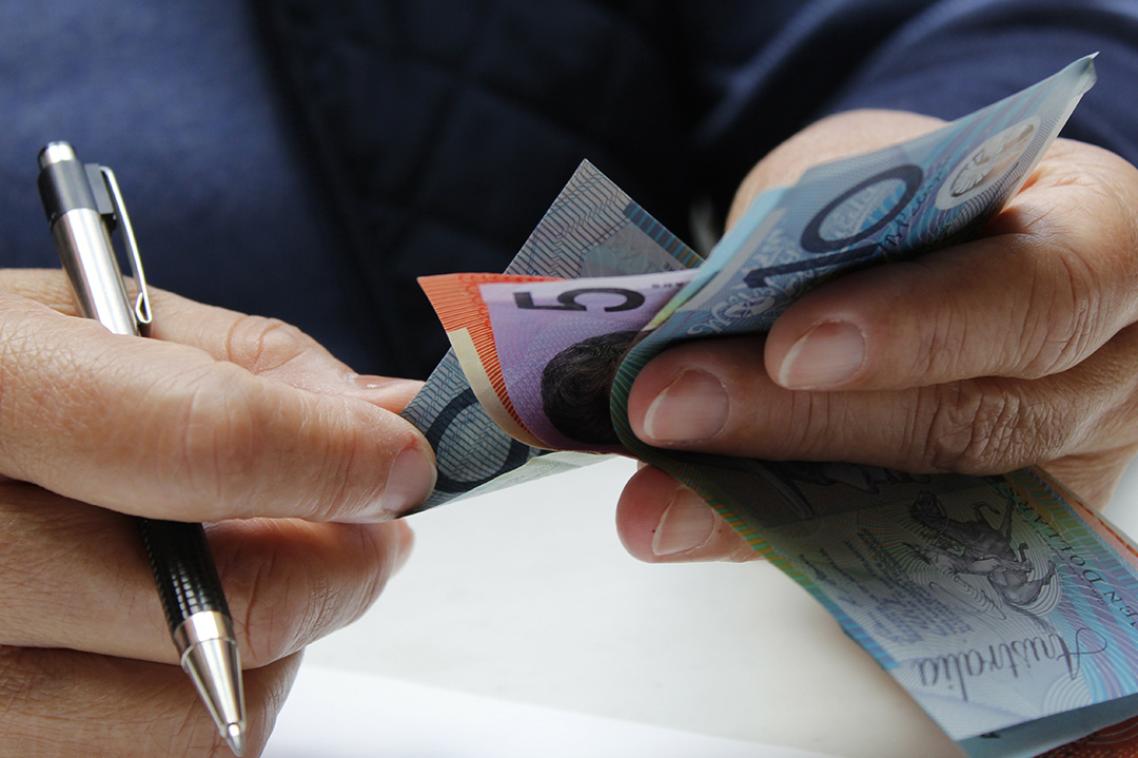 Close up of two hands holding a pen and counting money.
