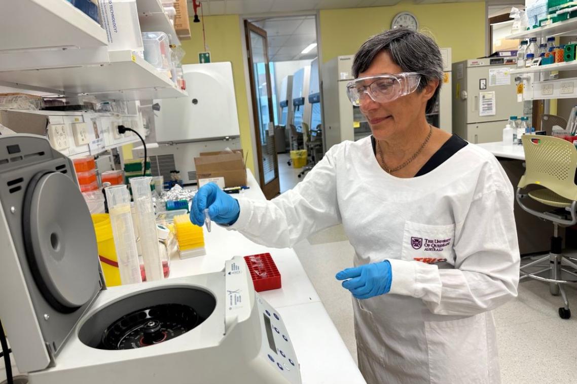 A woman in a lab coat looking into a large centrifuge 