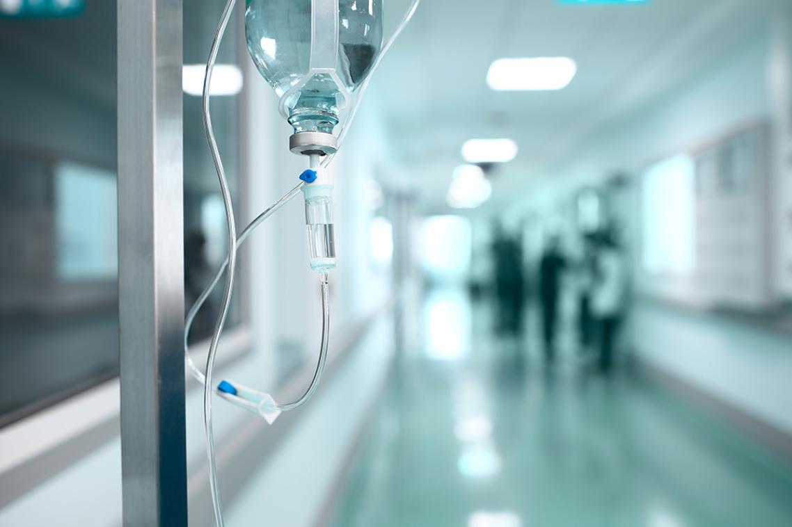 An infusion drip stands in a hospital corridor. 