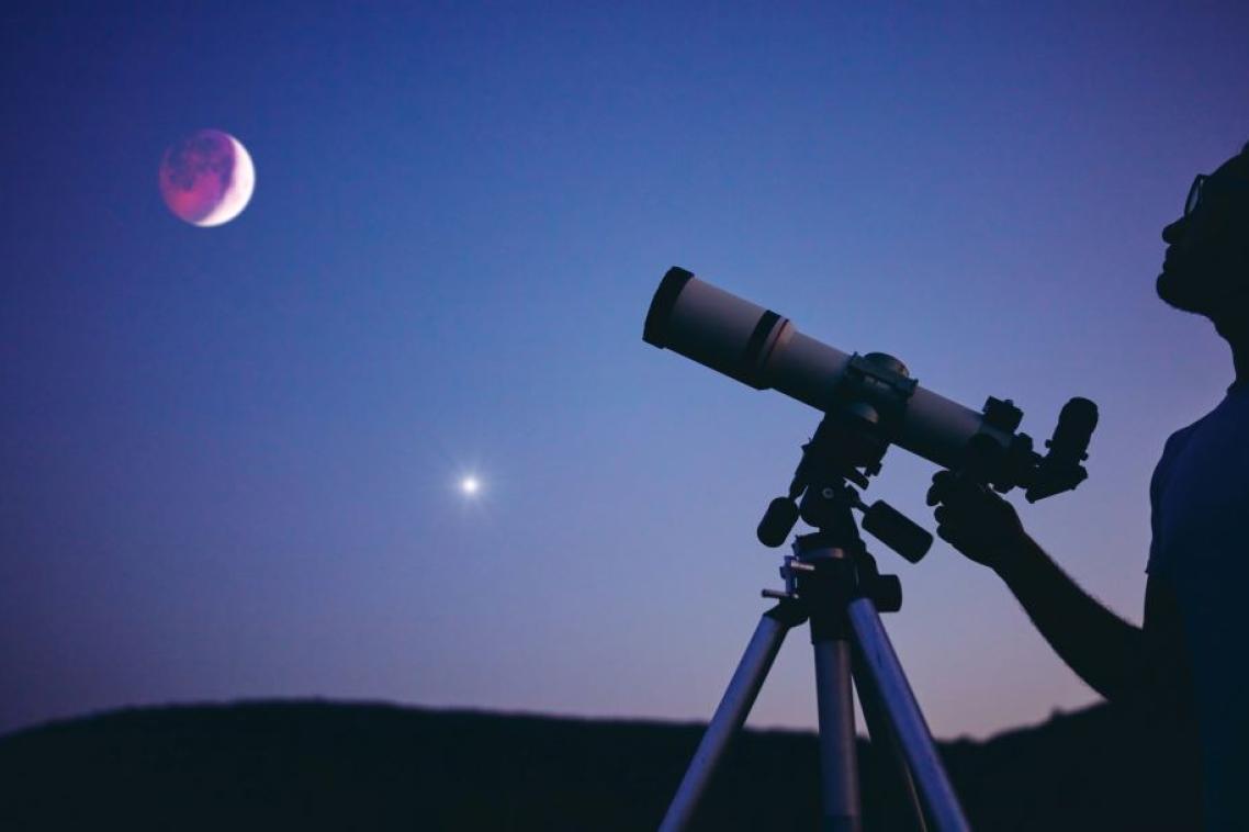 A man looking through a telescope at the night sky