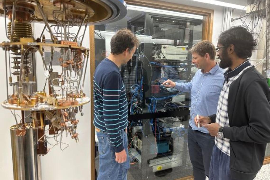 Three men in a lab looking at equipment.