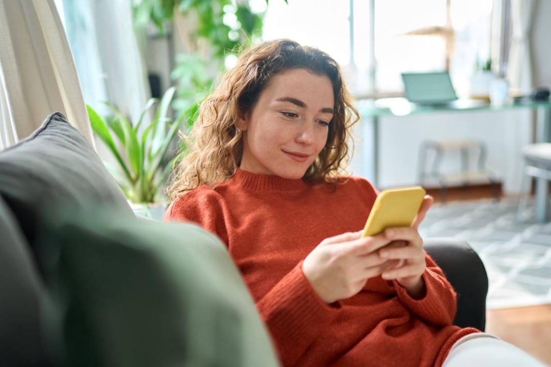 Woman sitting on a lounge looking at her smart phone.