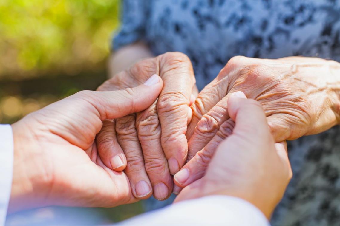 Close up of an older set of hands holding a younger set of hands