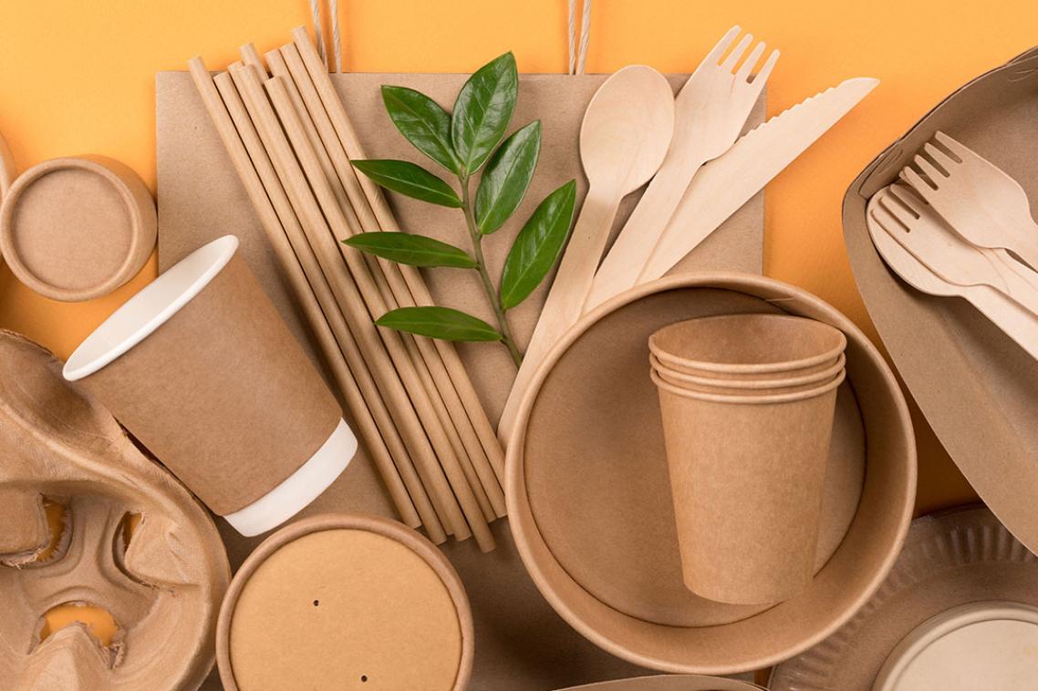 Cardboard packaging, including bowls, spoons, and straws laid out on the table