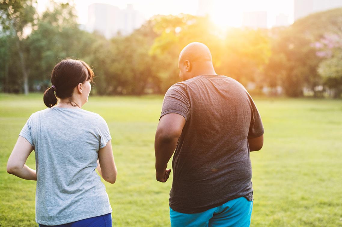 A man and woman are jogging through a park.