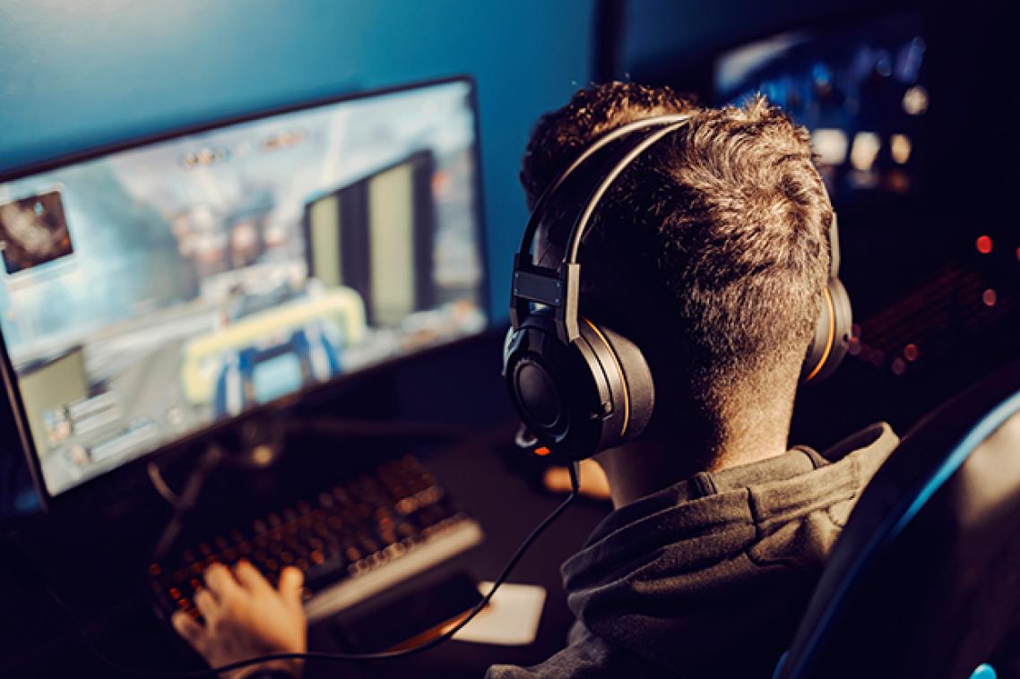 Person sitting at computer playing a game with headphones on