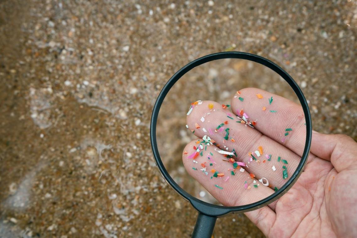 Magnifying glass holding up to a hand covered in small pieces of plastic