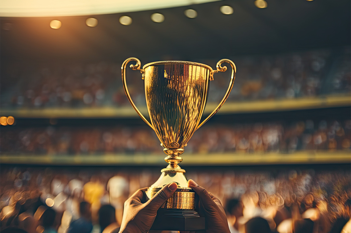 A gold trophy being held up in a stadium.