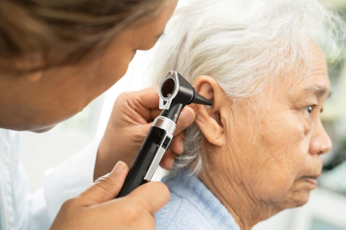 A close up of a audiologist inserting a hearing device into a patient's ear