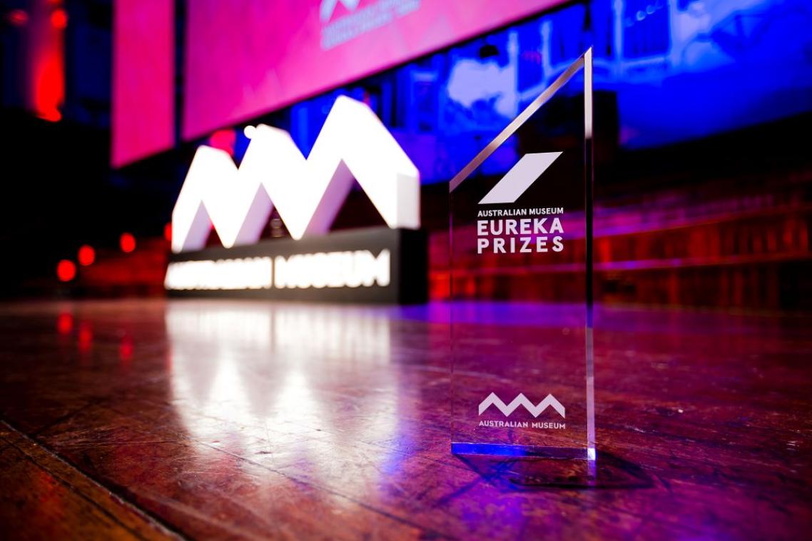 A glass Eureka Prize trophy on a wooden stage.
