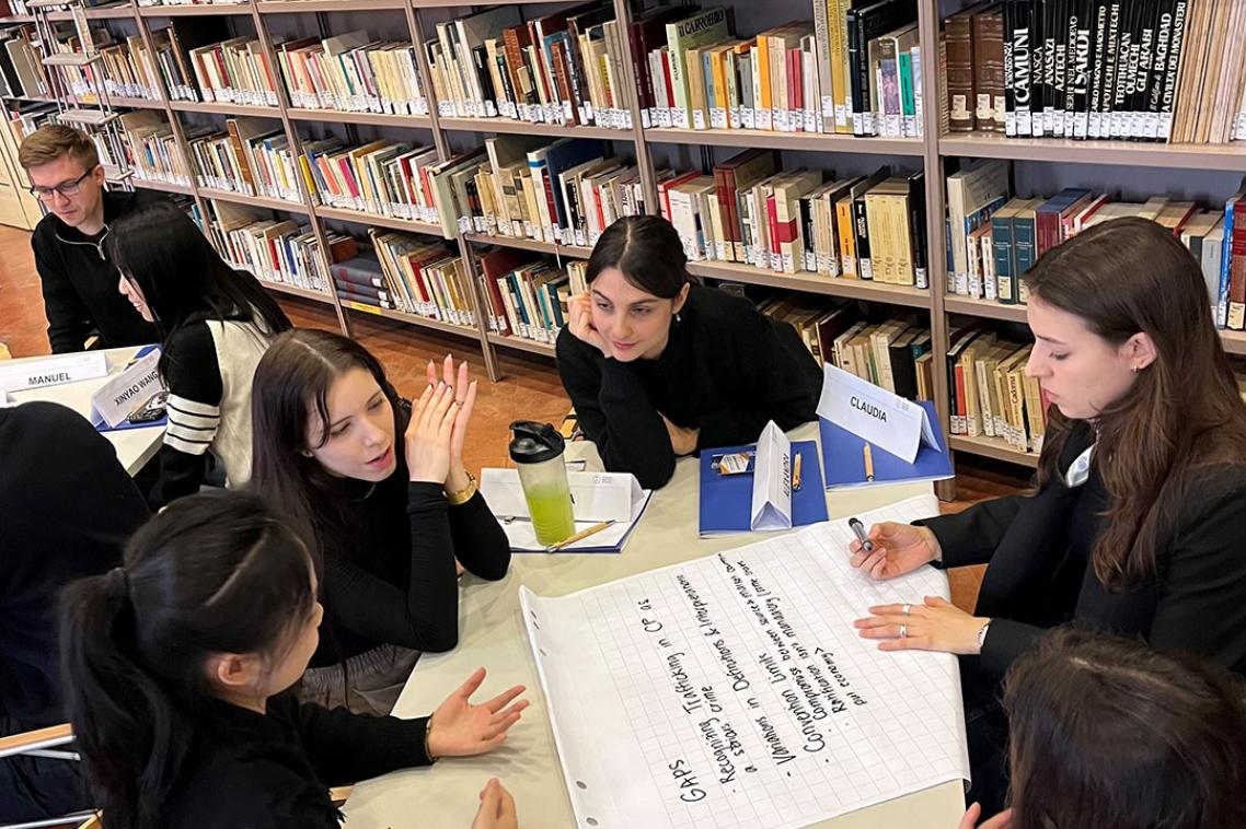 A group of students sitting around a table writing on a large piece of paper