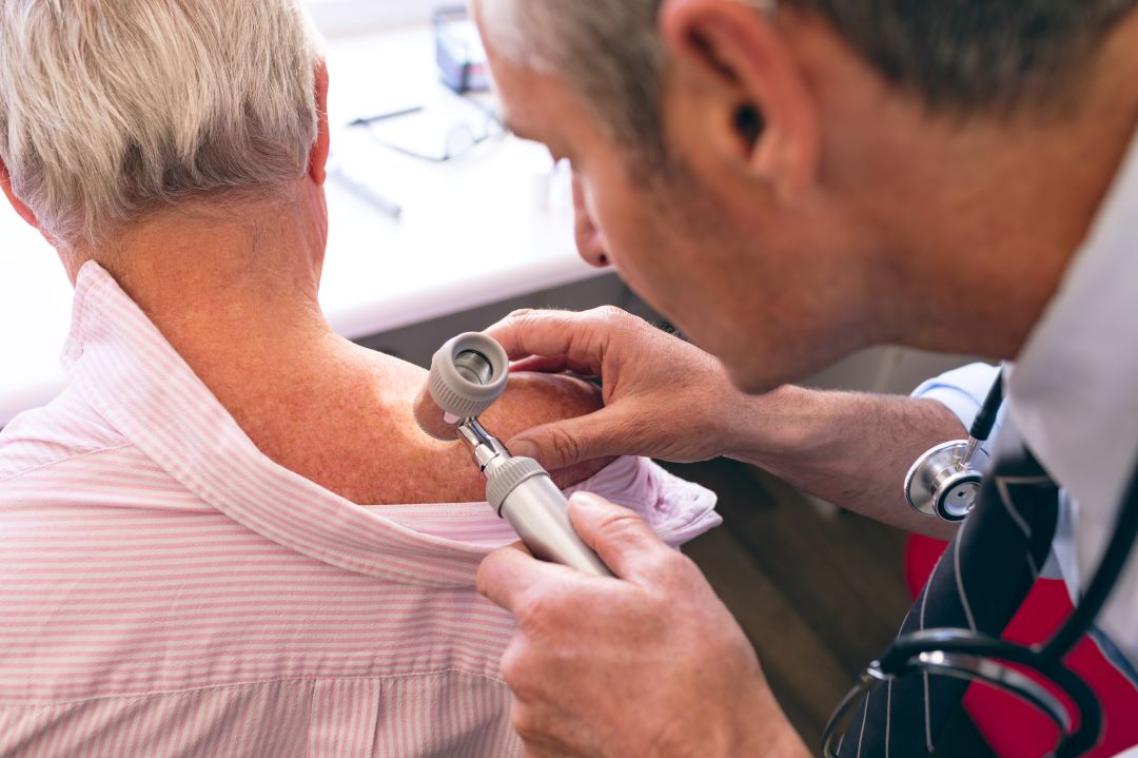 Doctor examining a patient's skin on their back.