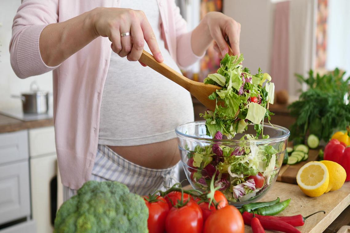 Pregnant woman makes a healthy salad.