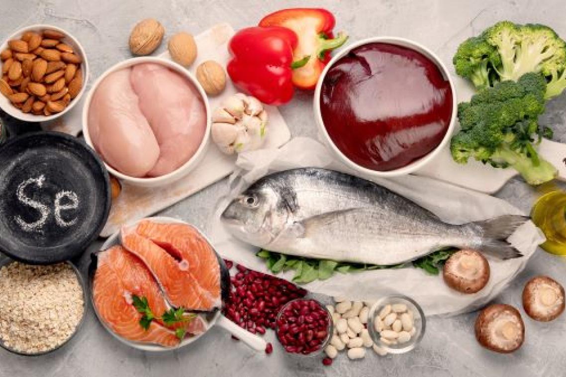 A variety of food sitting closely on a table including chicken, fish, broccoli, capsicum, almonds, garlic