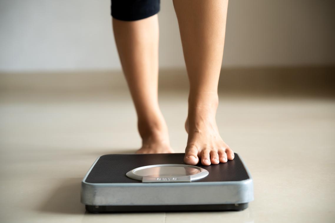 A woman's lower legs pictured standing on weighing scales.