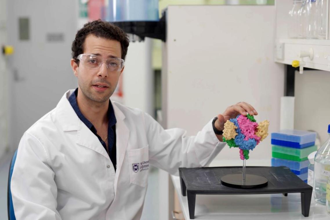 a man in a white coat sits next to a multi-coloured model