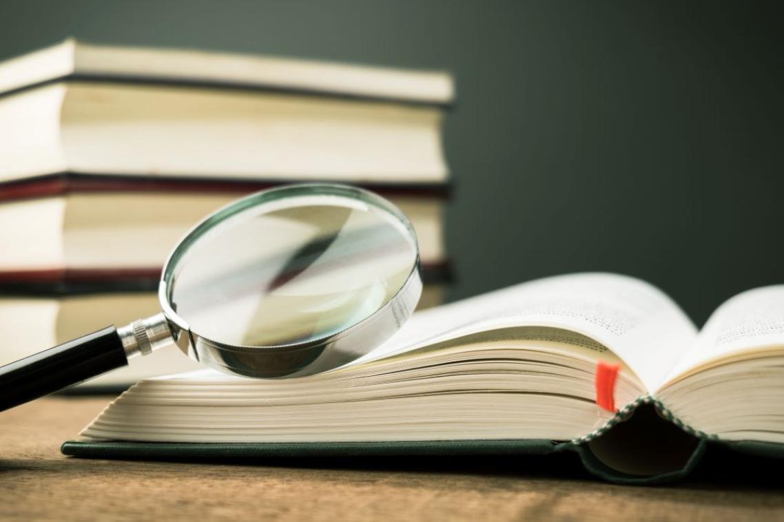 An open book with a magnifying glass sitting on top