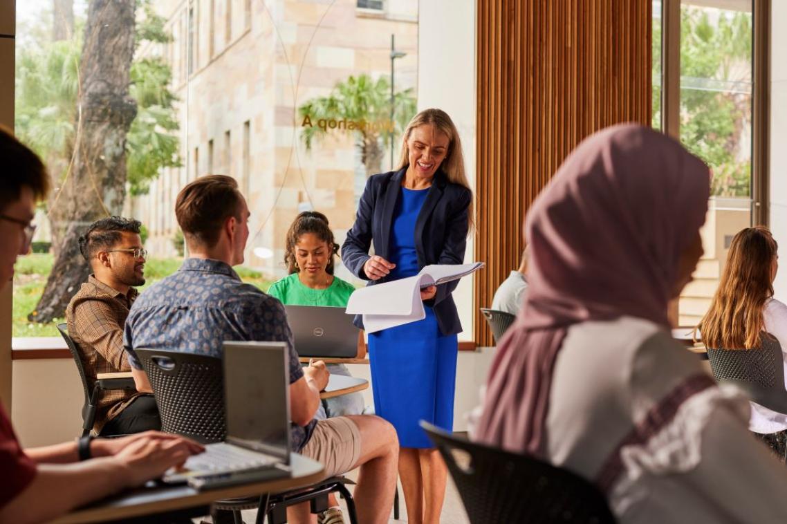 A woman in a blue blazer teaching a group of students in a classroom