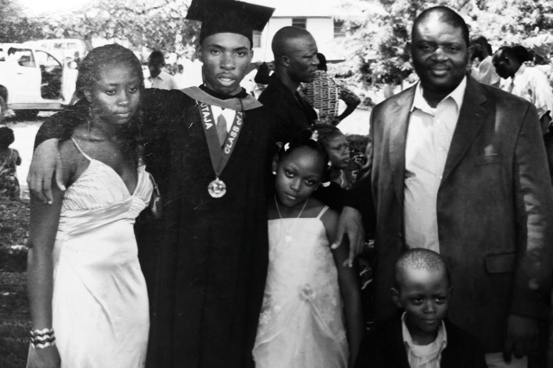 A man in graduation cap and gown poses with his family.