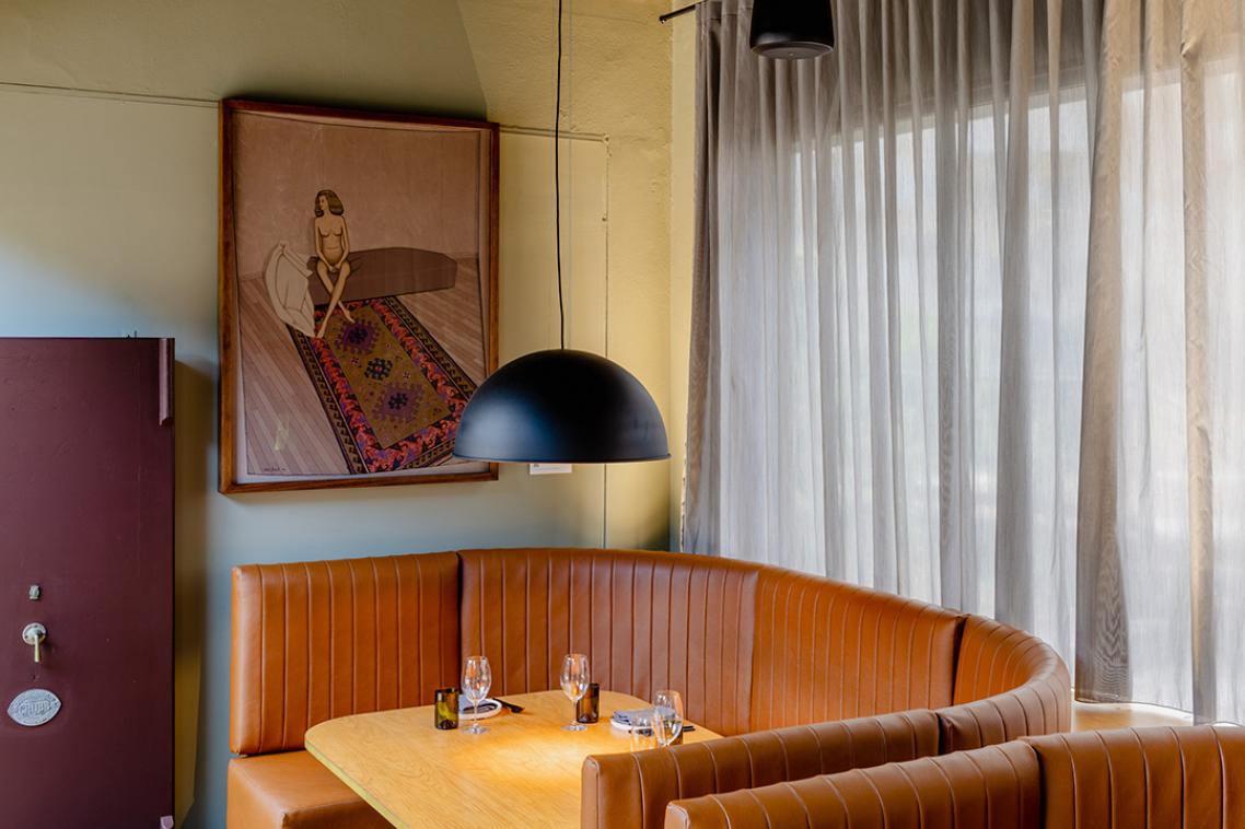 An artwork on a wall behind a cafe booth with glassware and dinnerware on the table