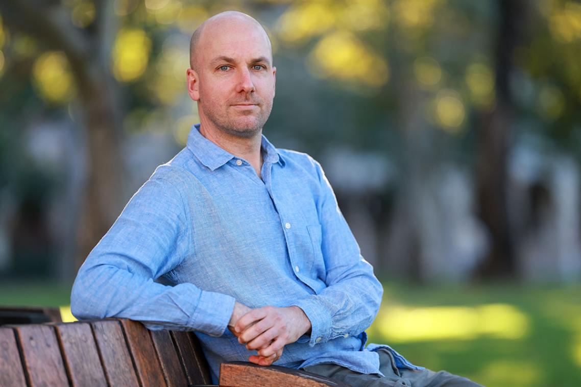 A man in a blue shirt sitting on a park bench