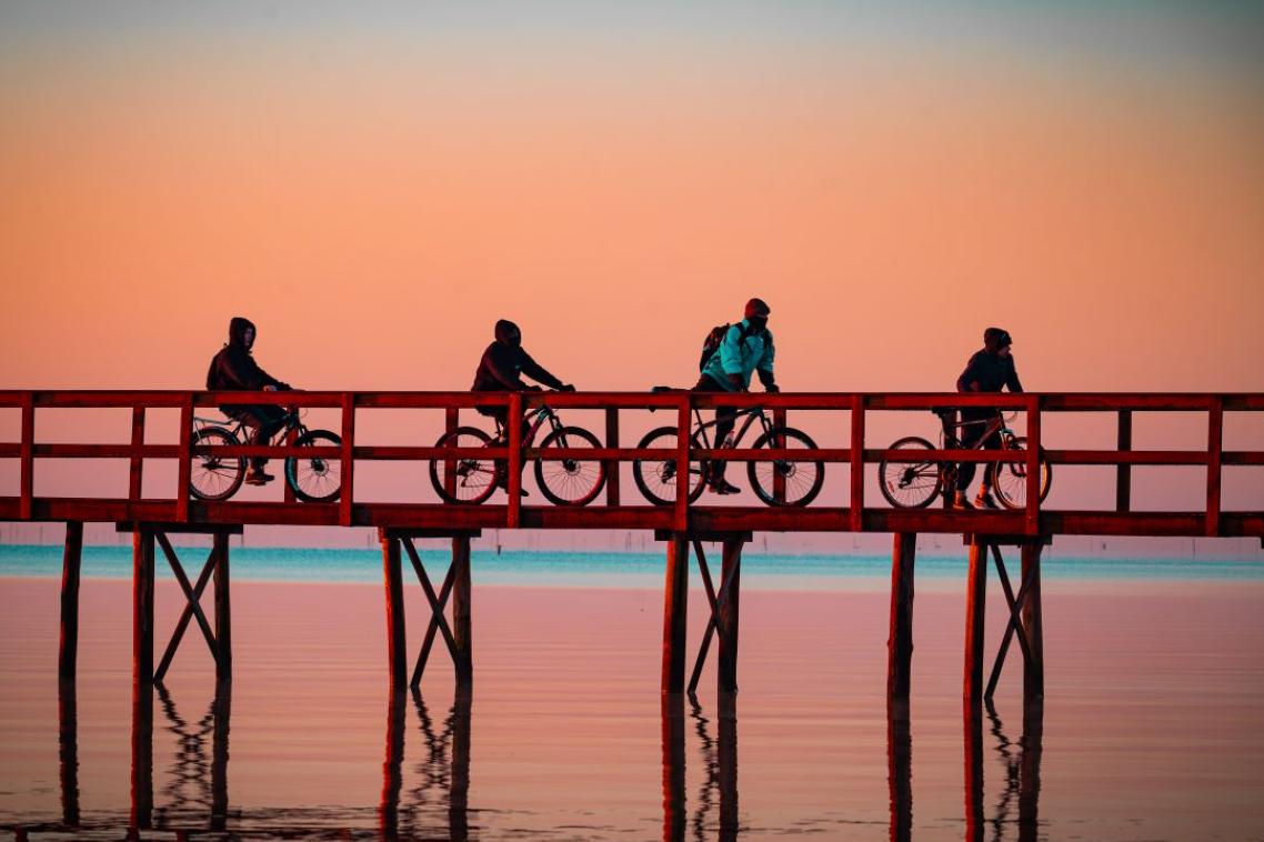 Four cyclists gliding along in the sunrise at the Trapiche in Pelotas, Brazil.