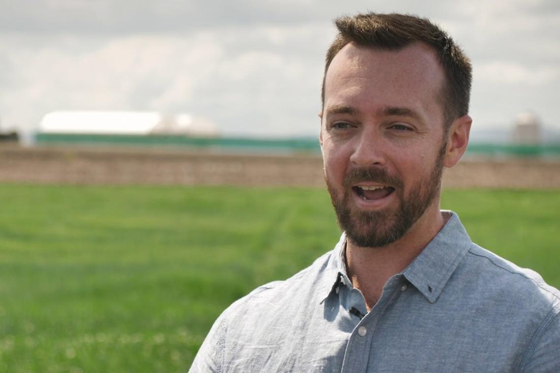 A UQ researcher stands in a crop field