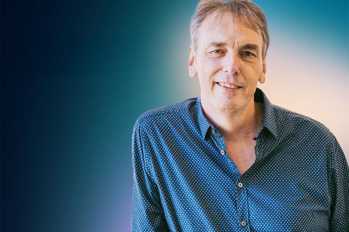 A man in a blue shirt smiling at the camera
