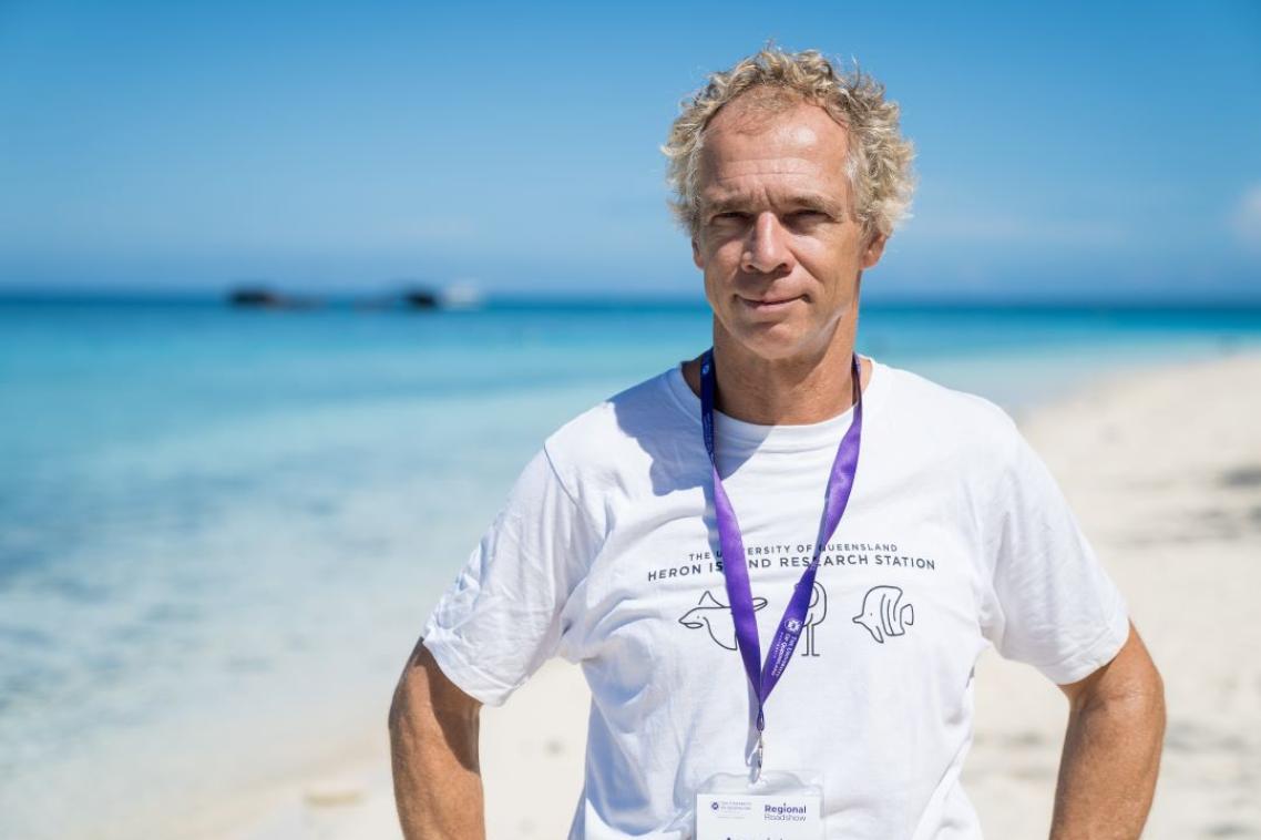 A man standing on a white sand beach. 
