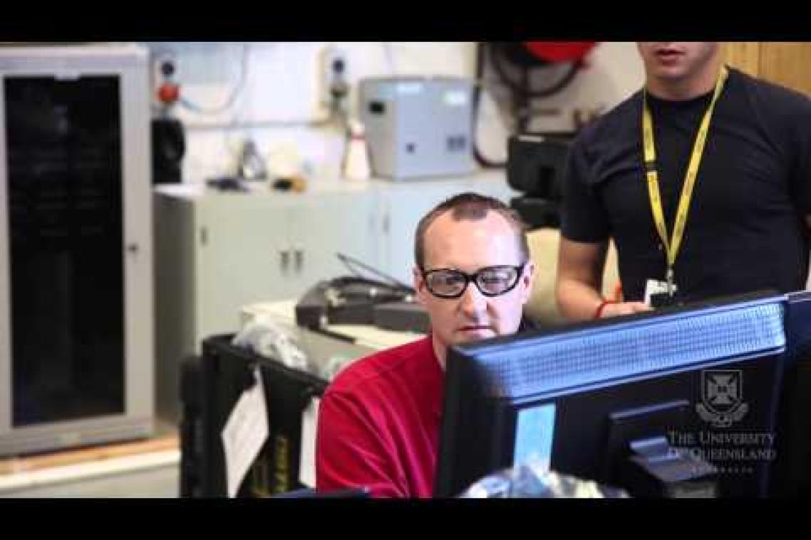 A UQ researcher with glasses looks at a computer