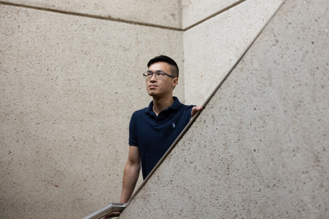 A man leaning on the banister of a staircase