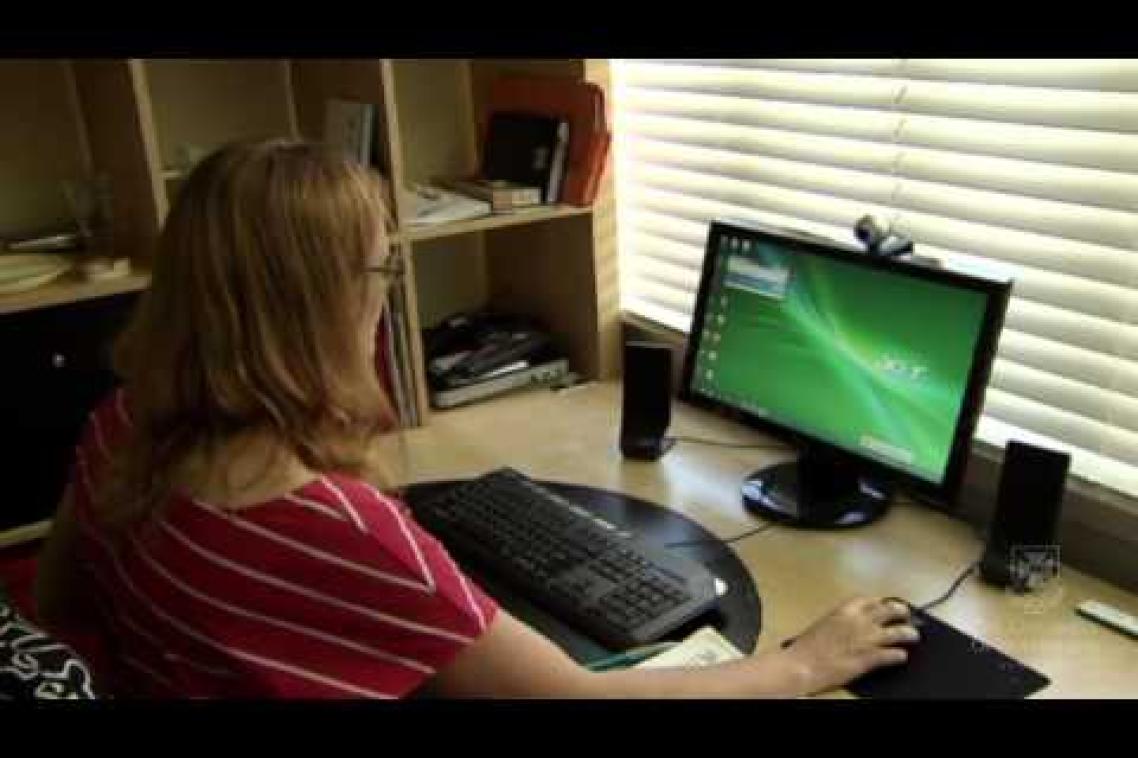 A woman sits in front of a computer screen
