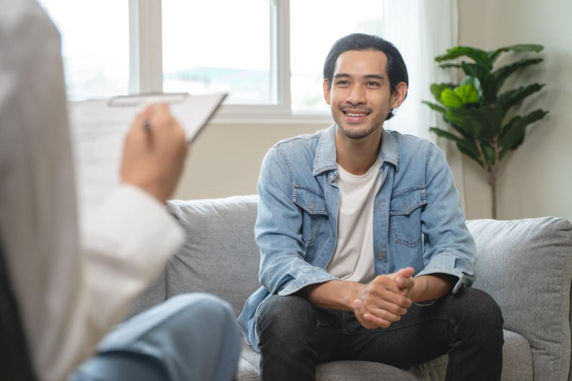 A man smiling, chatting to a health professional.